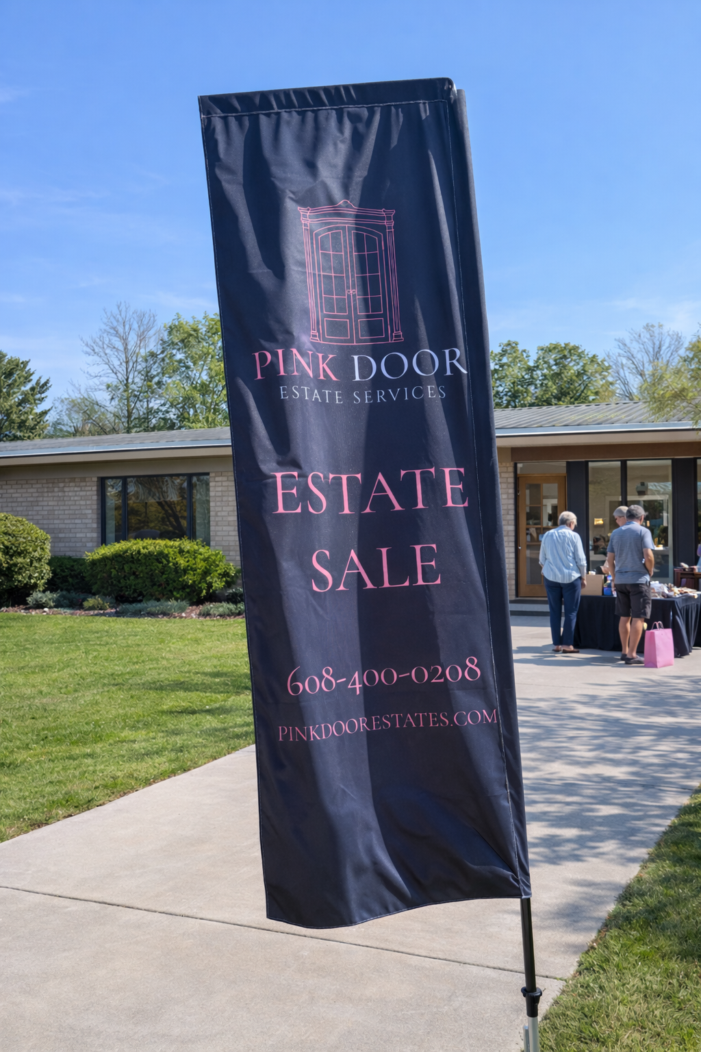 Vertical banner advertising estate sale by Pink Door Estate Services, with a pink outline of a door at the top, and contact information including phone number and website. In the background, a house with a few people outside near a table.