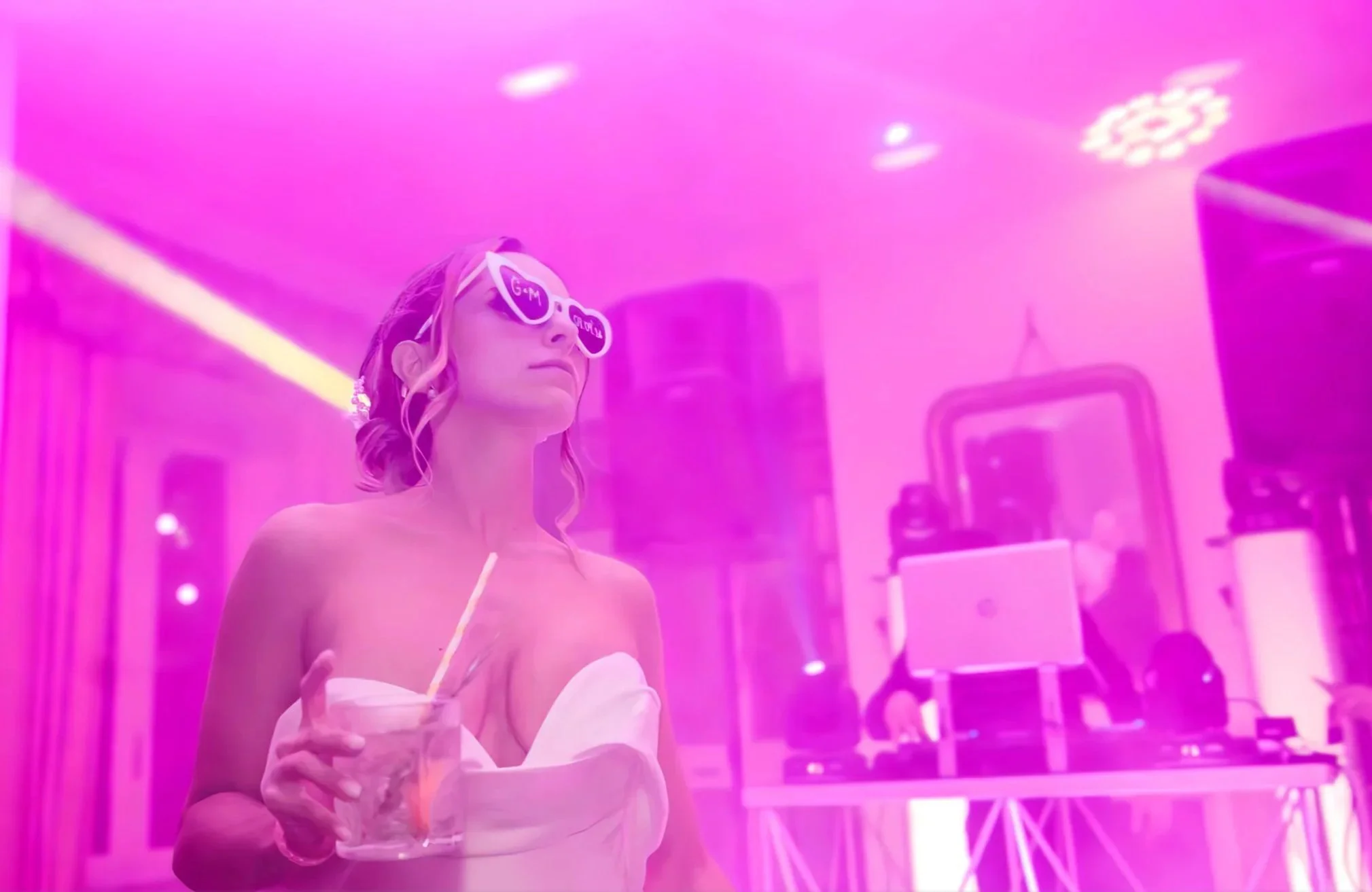 Divertimento e party nuziale: sposa con occhiali a cuore personalizzati e cocktail durante il DJ set di MDM Eventi.