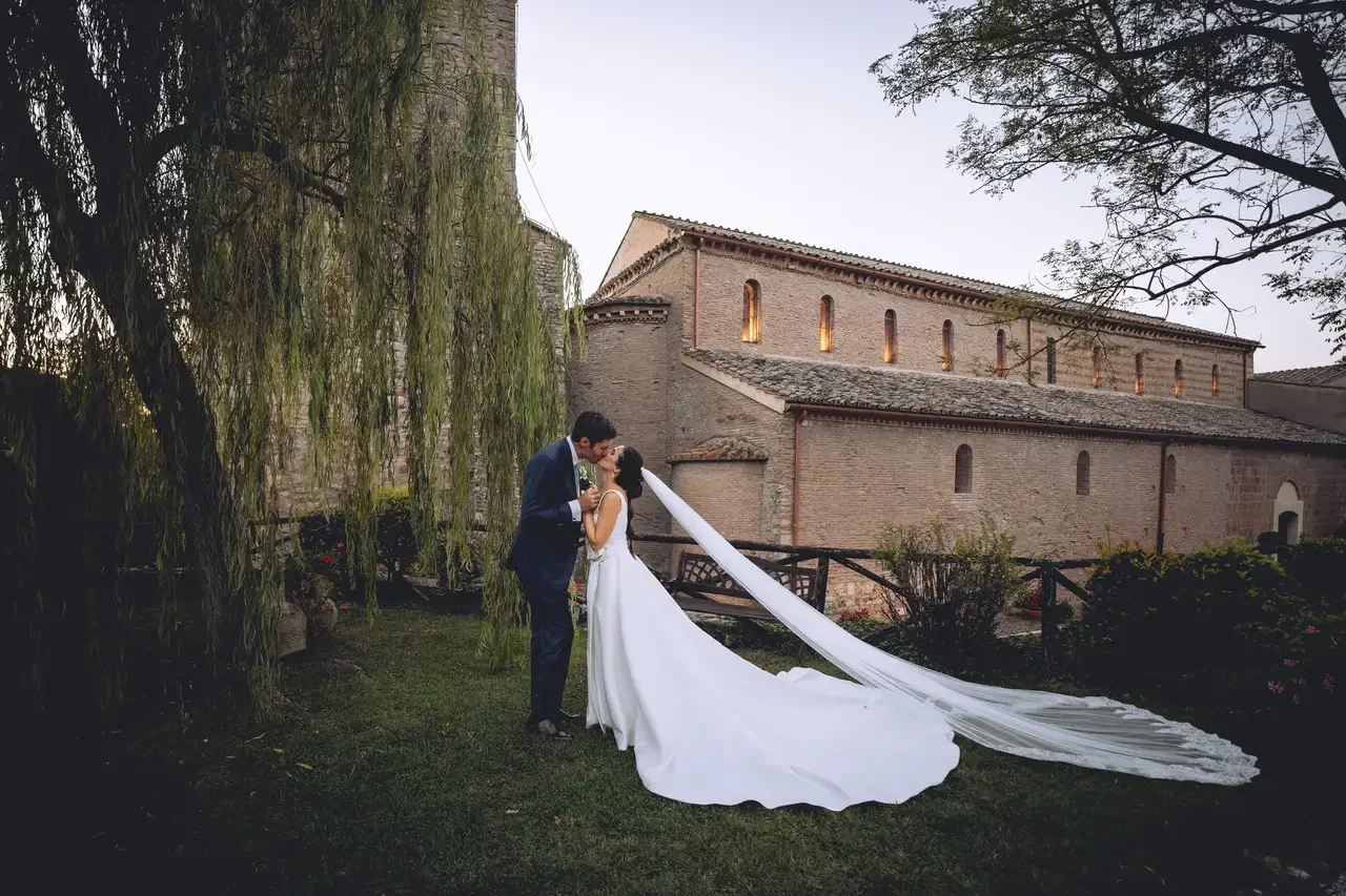 Sposi che si baciano nel giardino dell'Abbazia di Sant'Andrea in Flumine, atmosfera storica e romantica curata da MDM Eventi