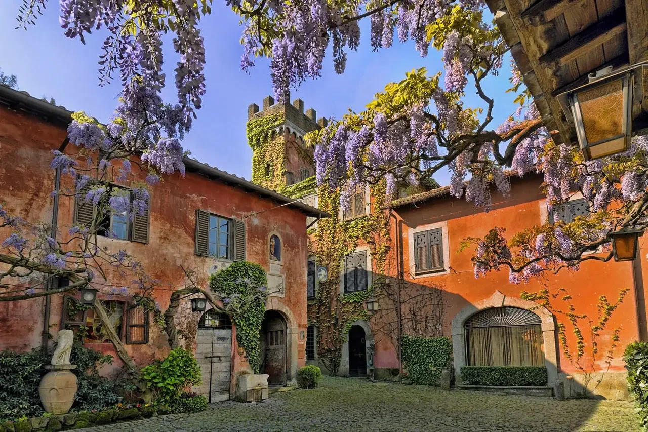 Scorcio suggestivo di un antico borgo per matrimoni con glicine in fiore e architettura storica italiana