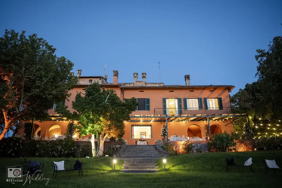 Facciata illuminata di Villa Senni durante un ricevimento serale, allestimento banchetto nuziale in giardino