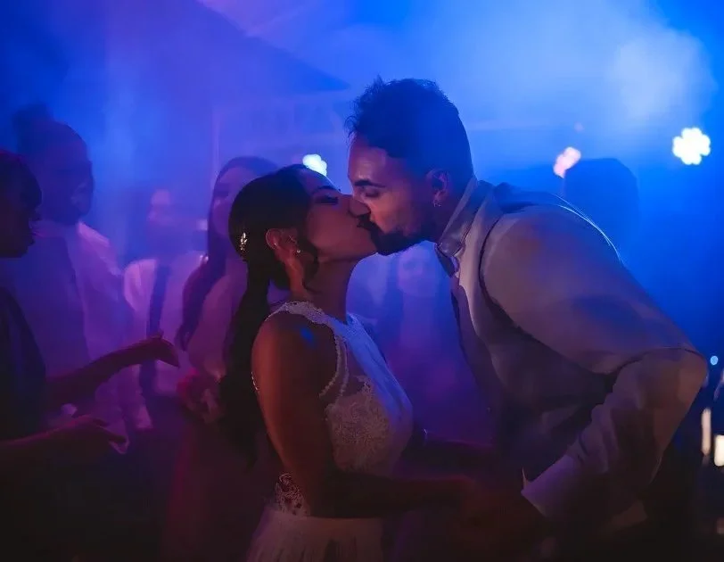 Animazione e DJ set per matrimoni: momento del bacio degli sposi sotto luci neon professionali durante la festa serale