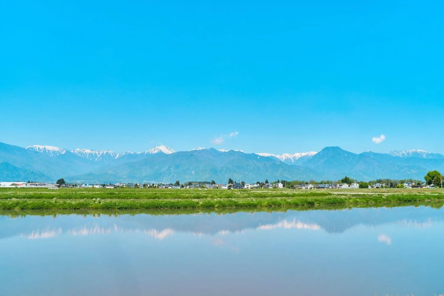Tabi trails Matsumoto tour view acroos still water to the Nagano mountains