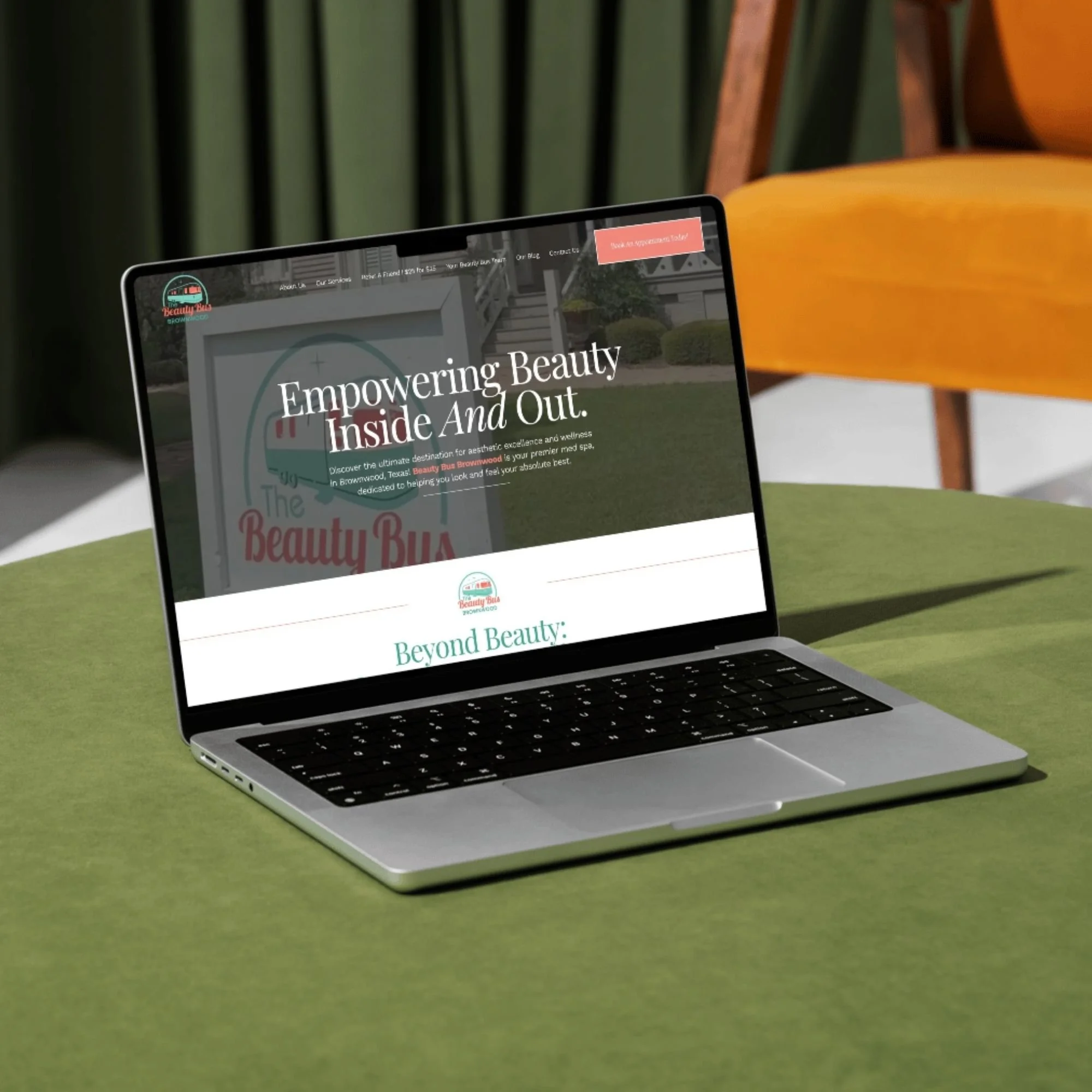 A laptop on a green surface displaying a website about beauty and wellness.