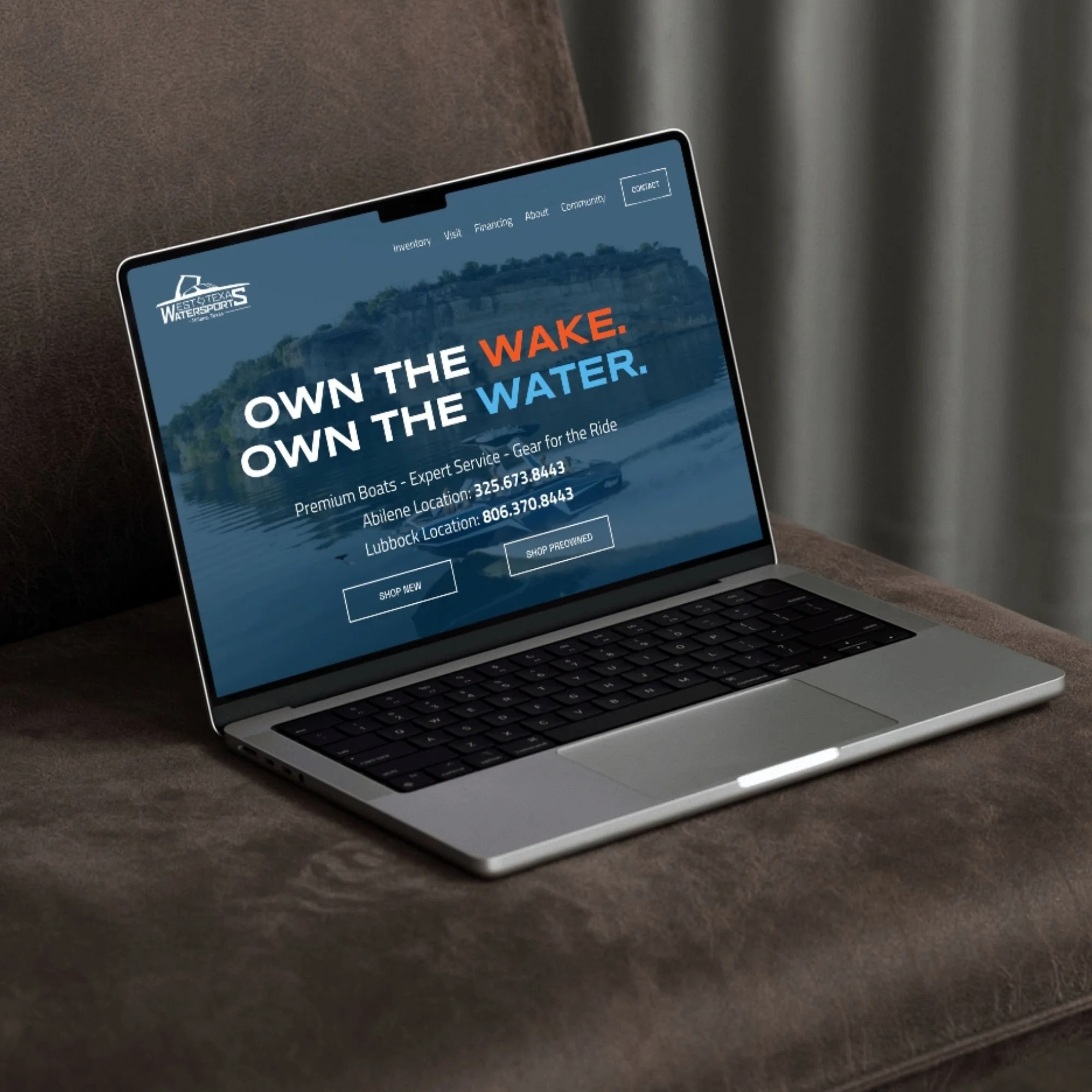 Laptop displaying a water sports company's website with a blue background, the text "OWN THE WAKE. OWN THE WATER," and contact information.