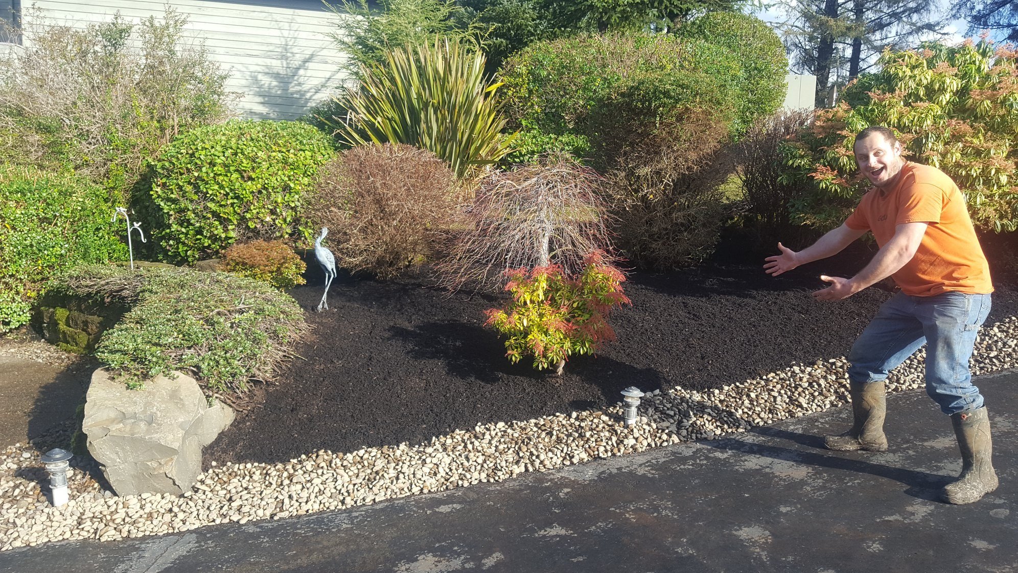 A landscaper standing in a yard showing off the work on the Oregon Coast.