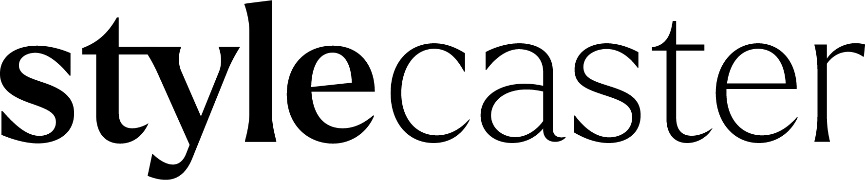 Black and white photo of a dog sitting outdoors in front of a wall and metal gate