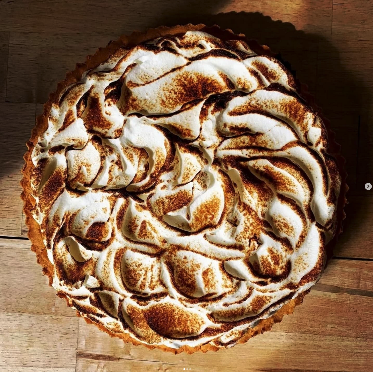 A lemon meringue pie topped with toasted meringue swirls.