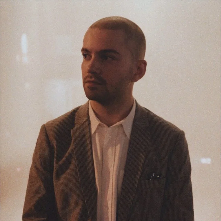 NYC Footy's Luca Silveira. Man in a suit looking to the side against a neutral background.