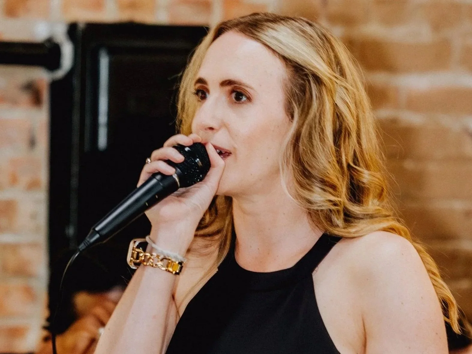A woman with red wavy hair holding a microphone and singing.