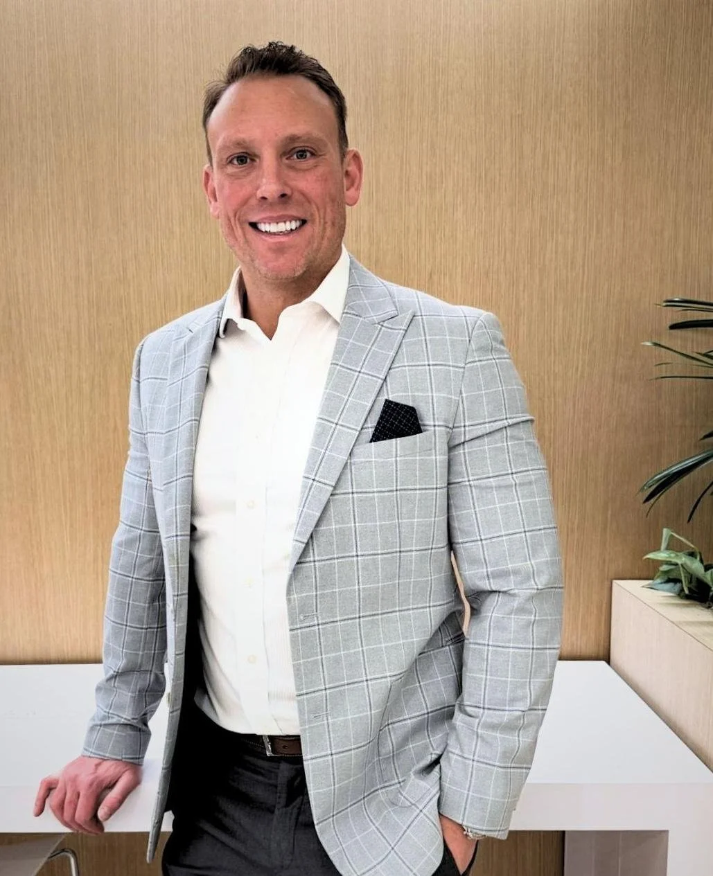 Christian Hale, founder of Core Group Consulting, standing relaxed and smiling in a modern office space — approachable, professional, no tie