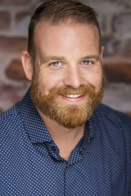 Smiling bearded man in a navy patterned shirt