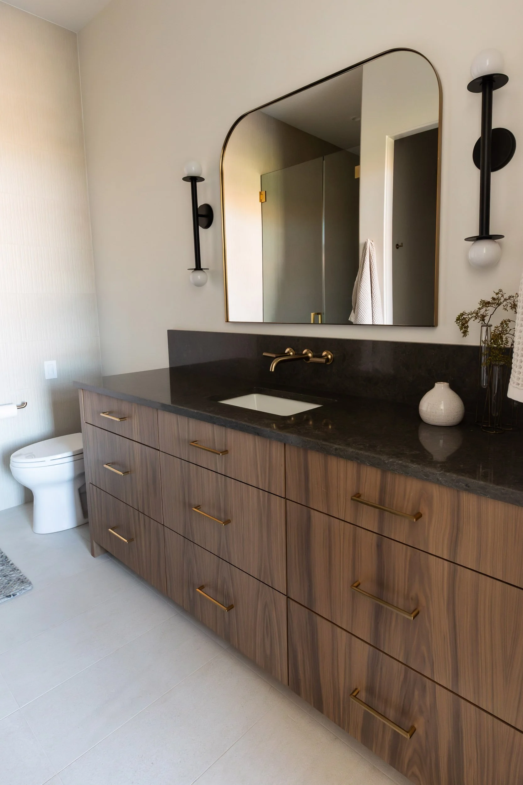 walnut bathroom with modern sconces and dark countertops
