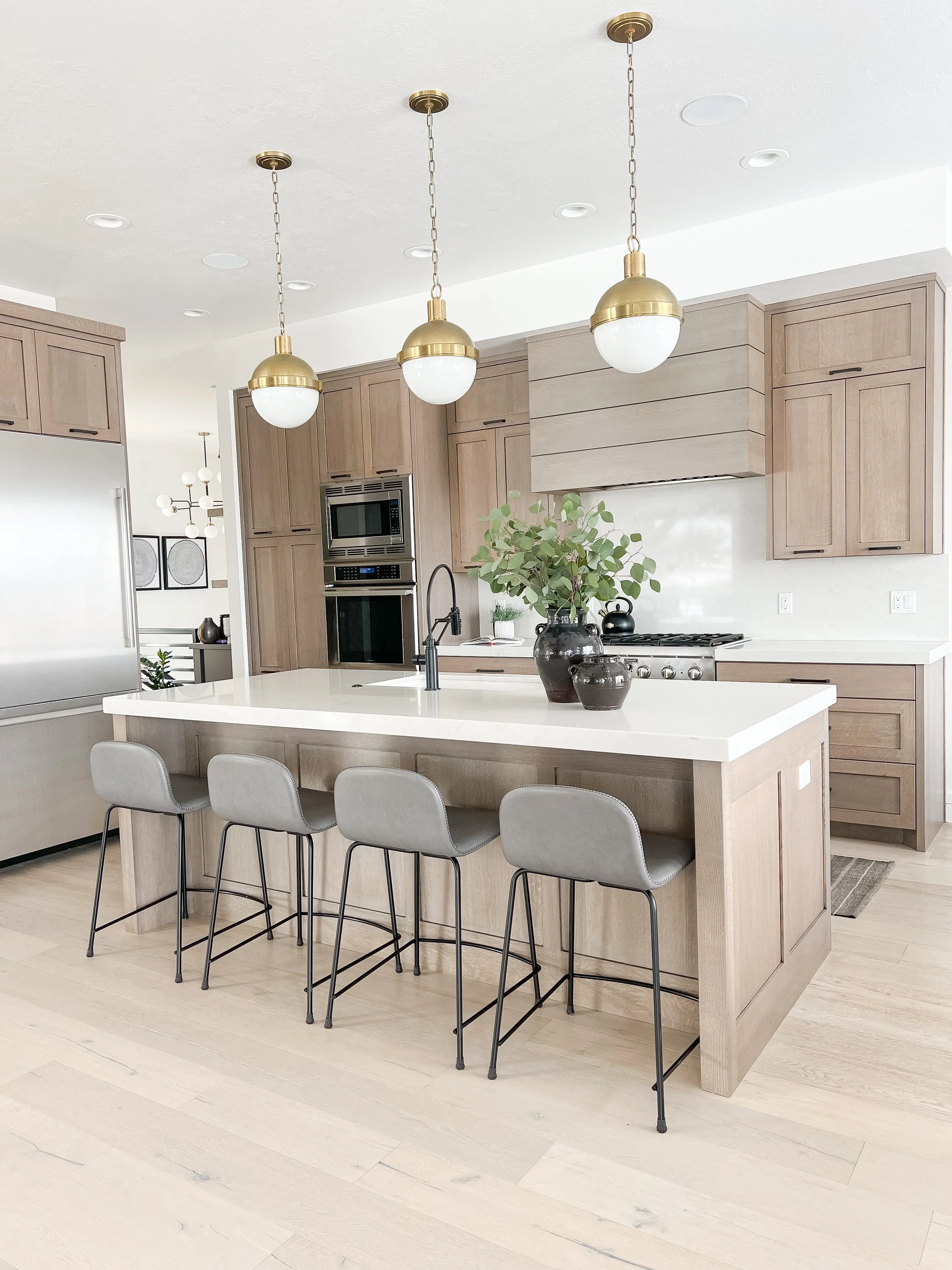 Light filled kitchen with white oak cabinets and gold pendants
