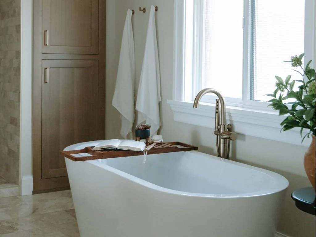Freestanding white soaking tub with a floor-mounted faucet in a spa-like bathroom retreat.