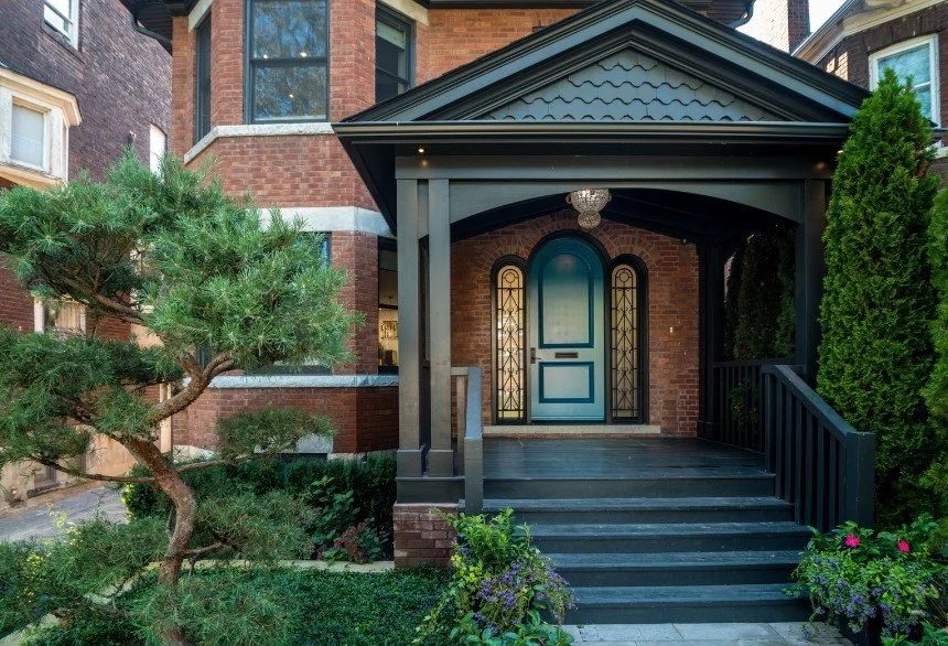 Traditional home entrance with an arched doorway, brick detailing, and a welcoming covered porch.