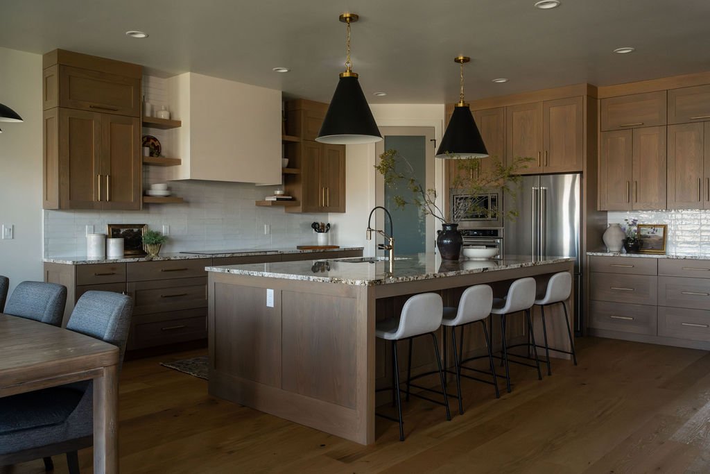 Modern kitchen with wood cabinetry, black pendant lighting, and LVP flooring for a warm and durable design.