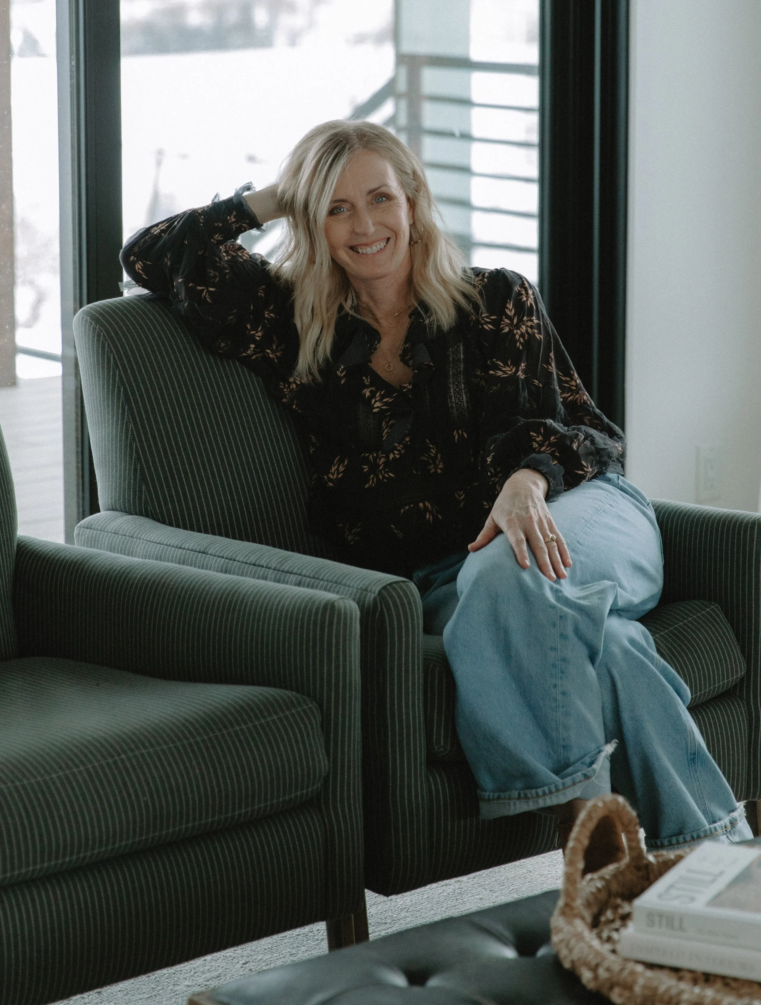 Interior designer, Jeri Cheney sitting on upholstered striped arm chair