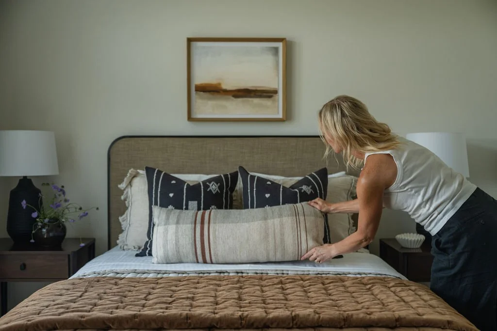Jeri adjusting the pillows on a bed