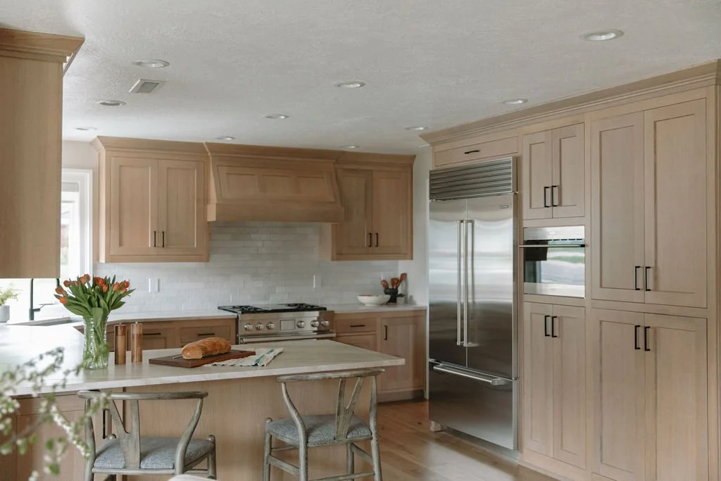 Renovated kitchen with custom range hood, panel-ready refrigerator, and a spacious island with elegant barstools.