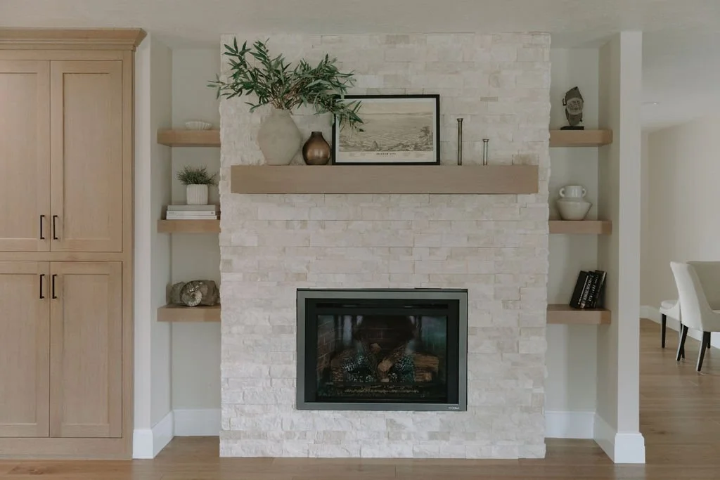 Stone fireplace with floating wood mantel, built-in shelves, and neutral decor for a cozy and modern living room design.