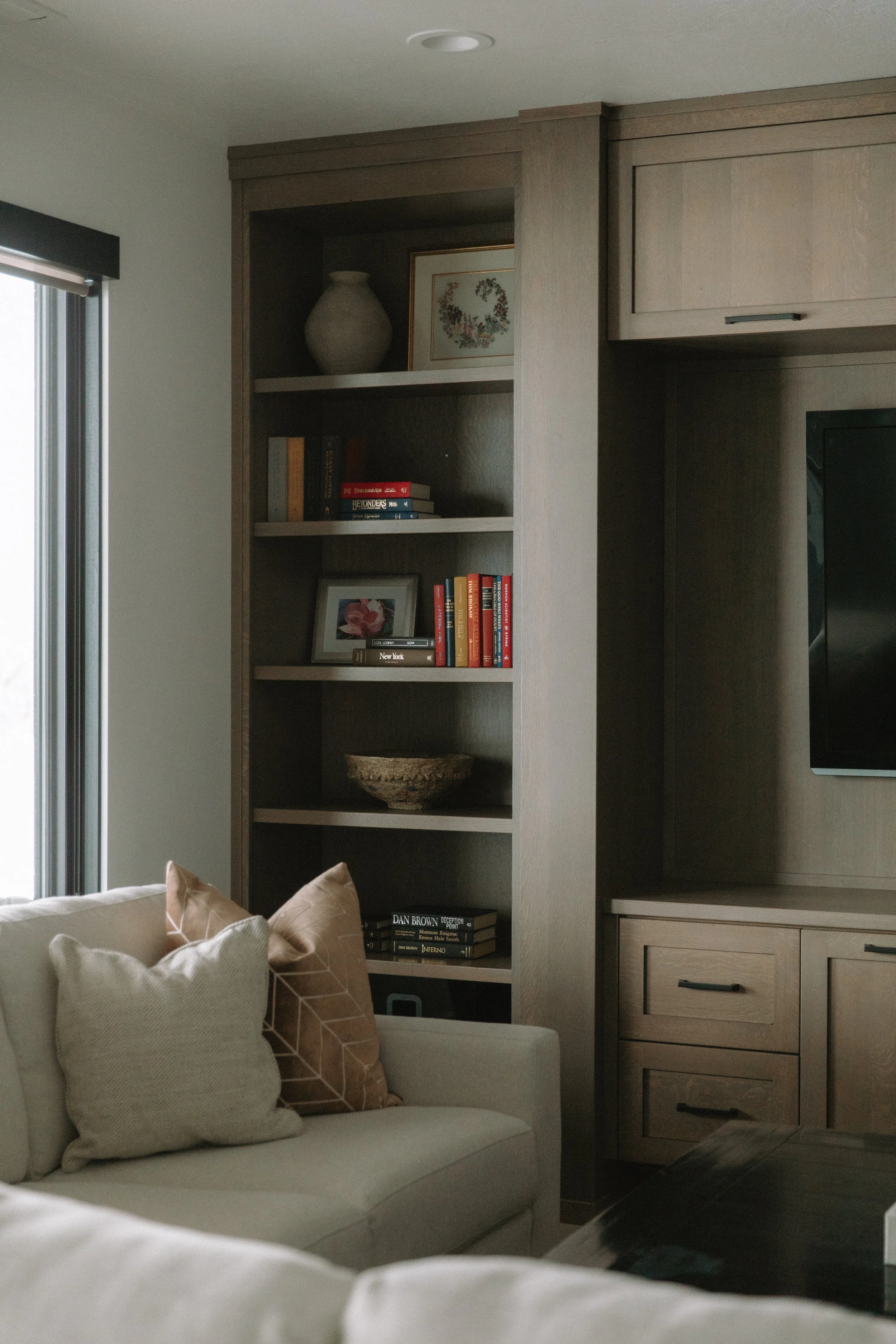 Living room wall shelving decorated with books, picture frames, and vases