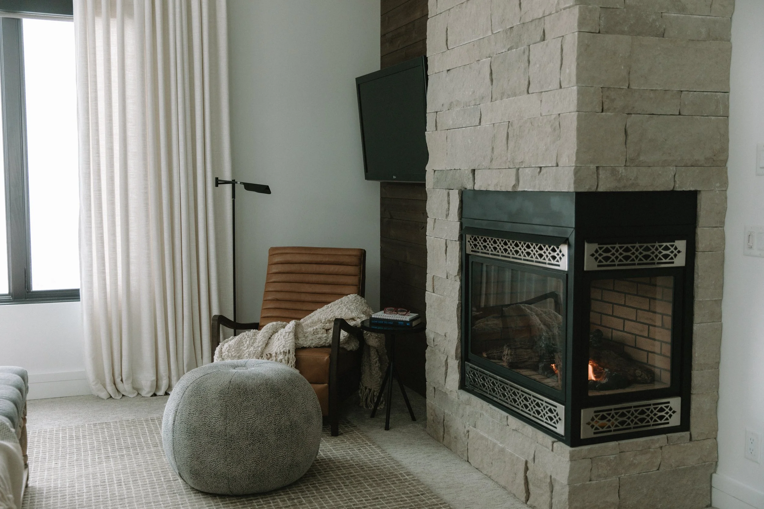 Reading nook consisting of armchair and footrest near a fireplace 