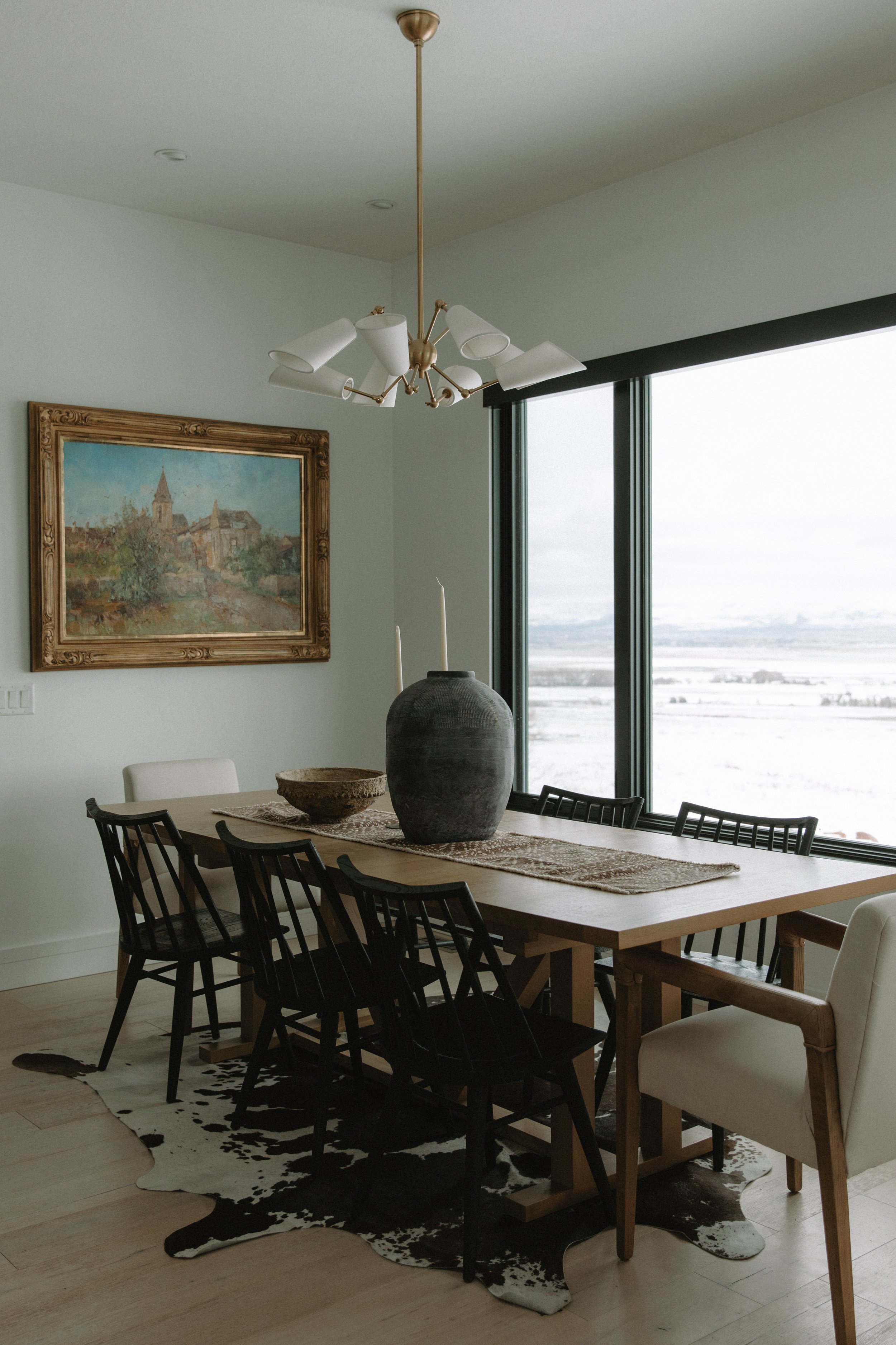 Modern and traditional dining room table with black chairs and cow hide rug