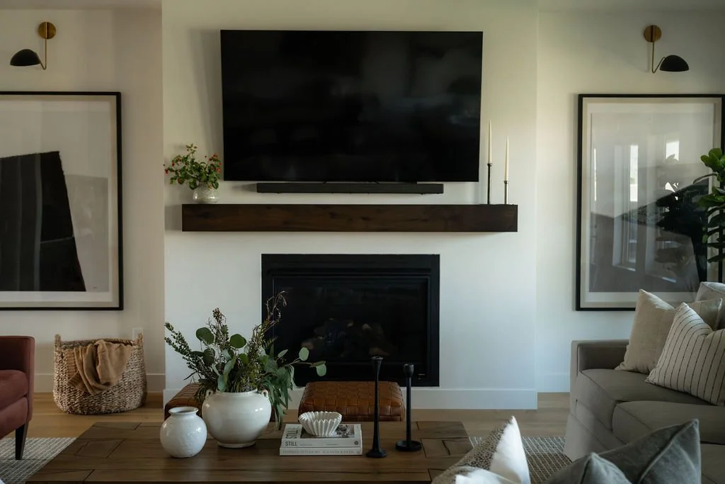 Modern living room with a sleek black fireplace, floating wood mantel, and neutral decor in a luxury vacation home.
