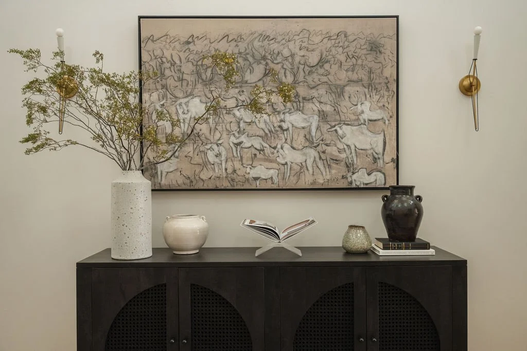 Statement art wall with large-scale abstract animal painting, black cane console, and curated ceramic decor pieces.