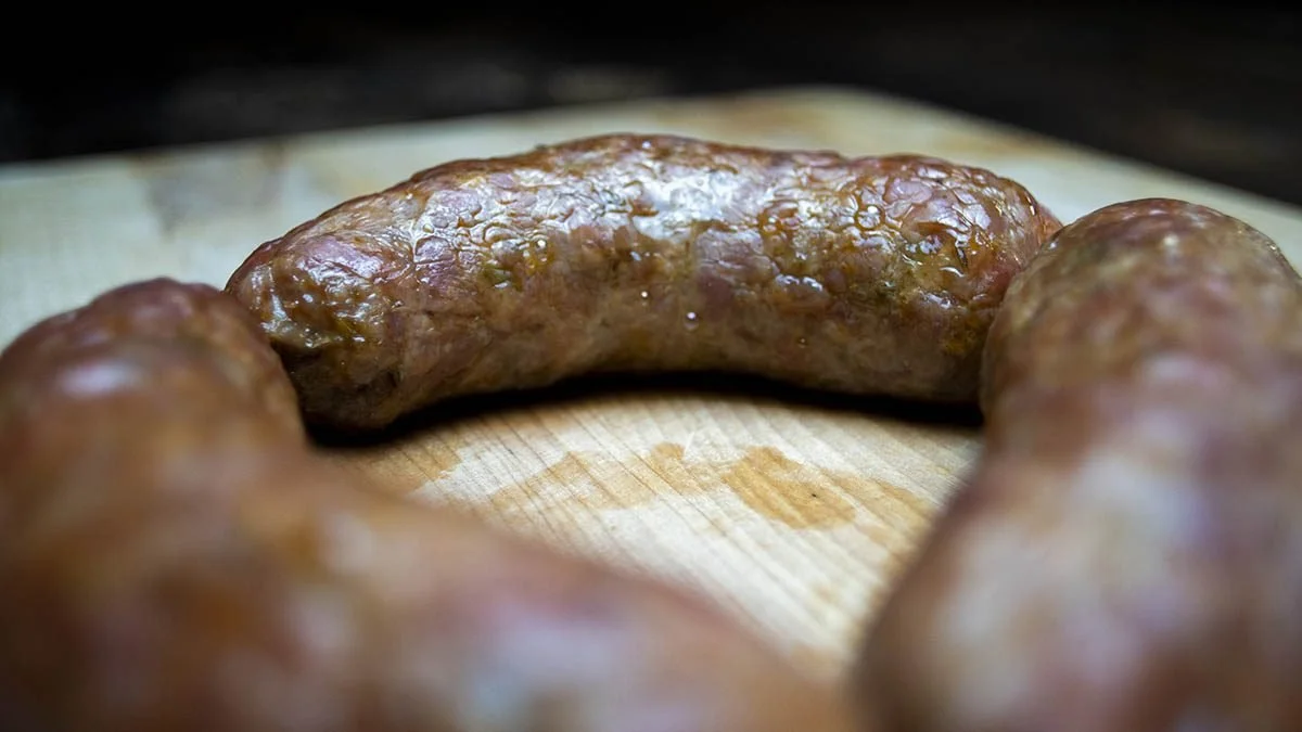 Close-up of cooked sausage links on a wooden cutting board.