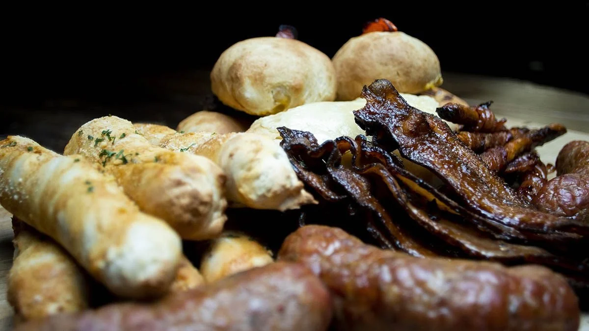 Assorted cooked breakfast foods including bacon, sausages, biscuits, and hash browns