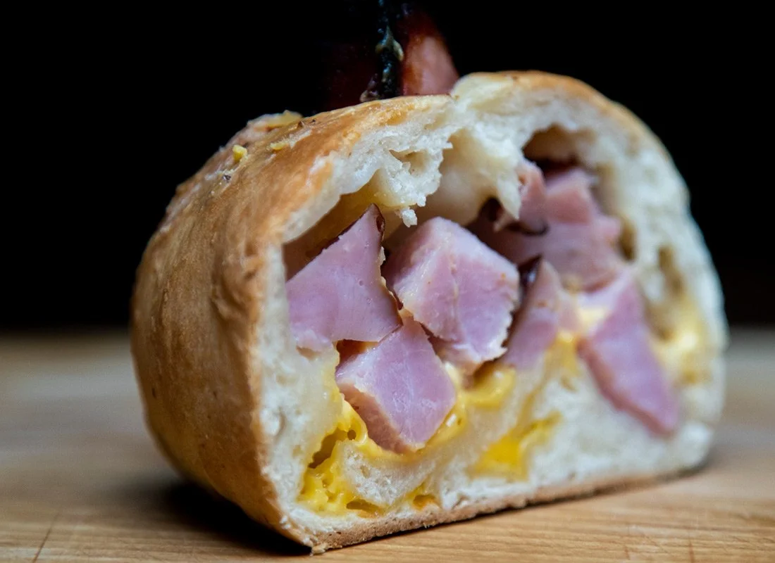 Half of a bread roll filled with ham and scrambled eggs