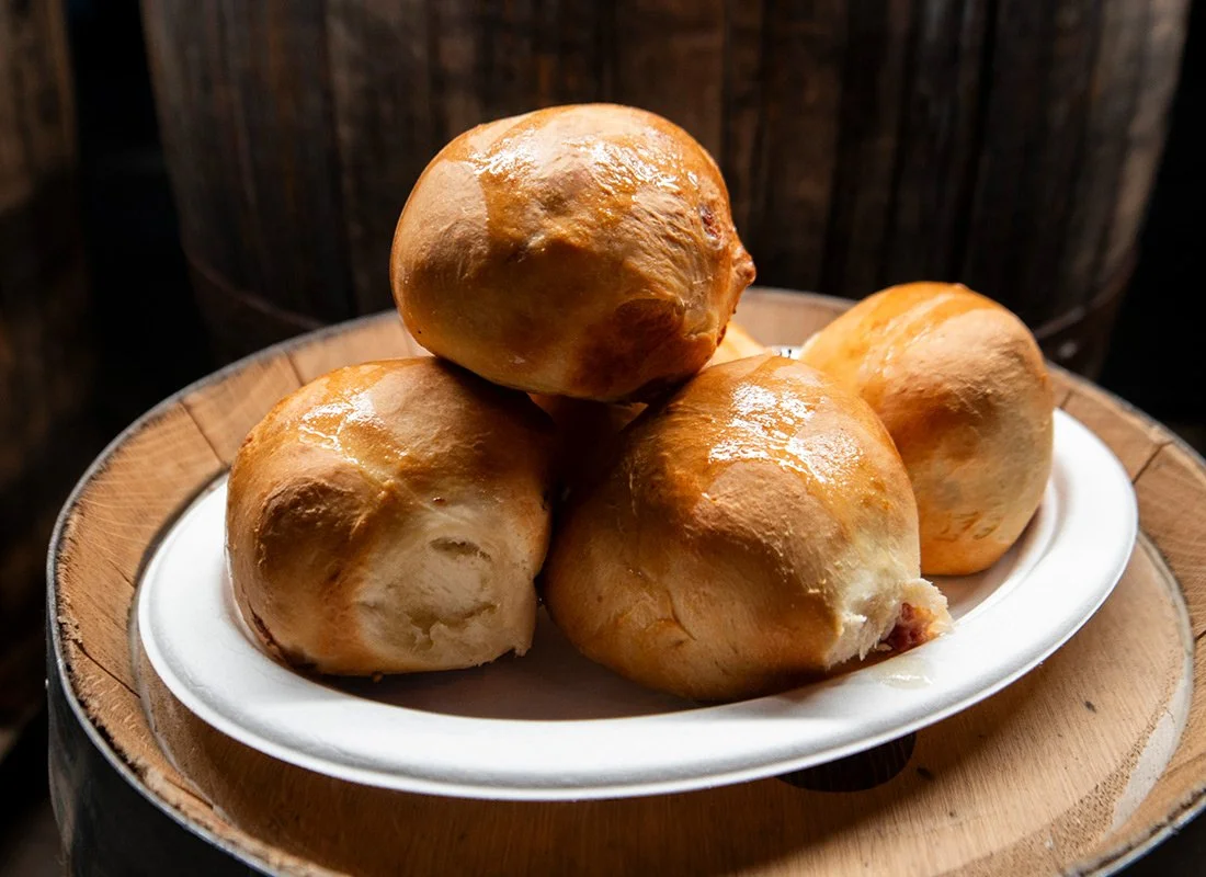 Four baked bread rolls on a white paper plate.
