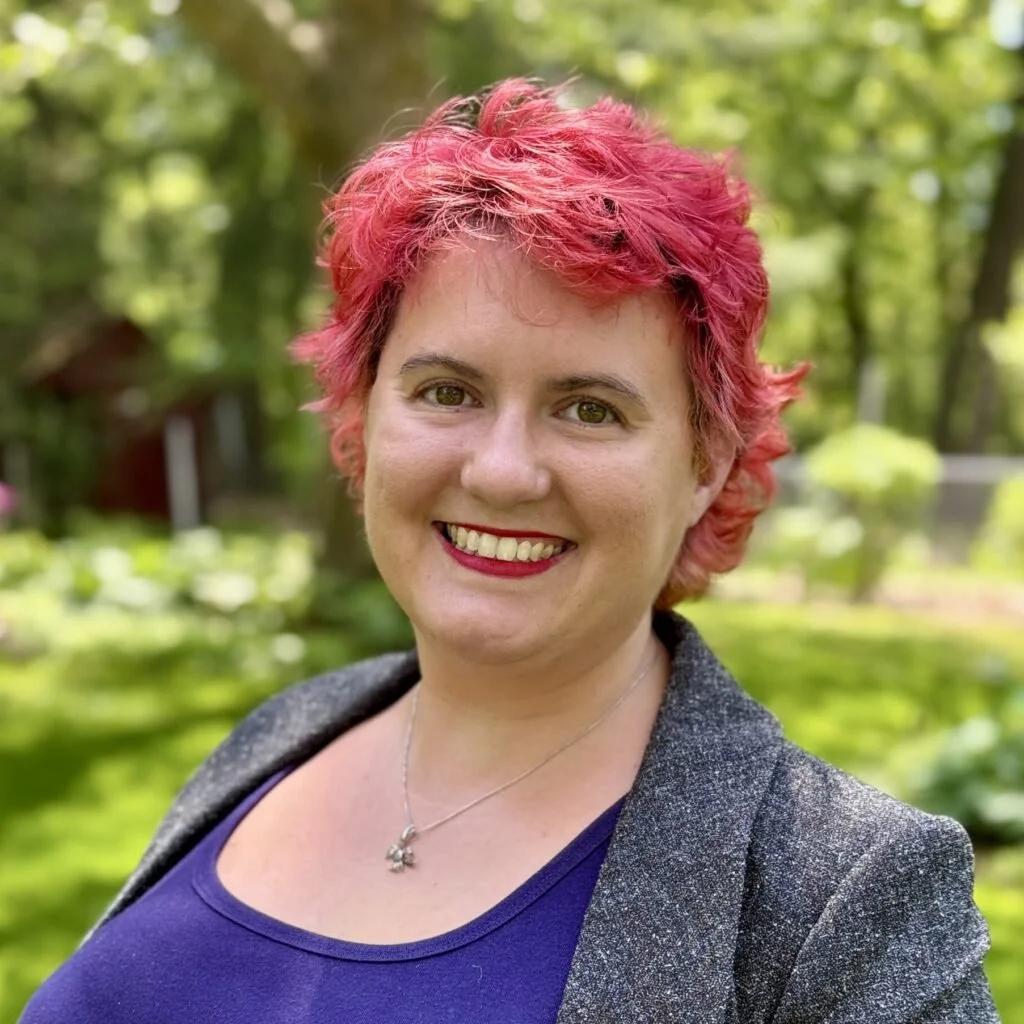 A photo of Samantha, a white woman with pink hair in a purple shirt.