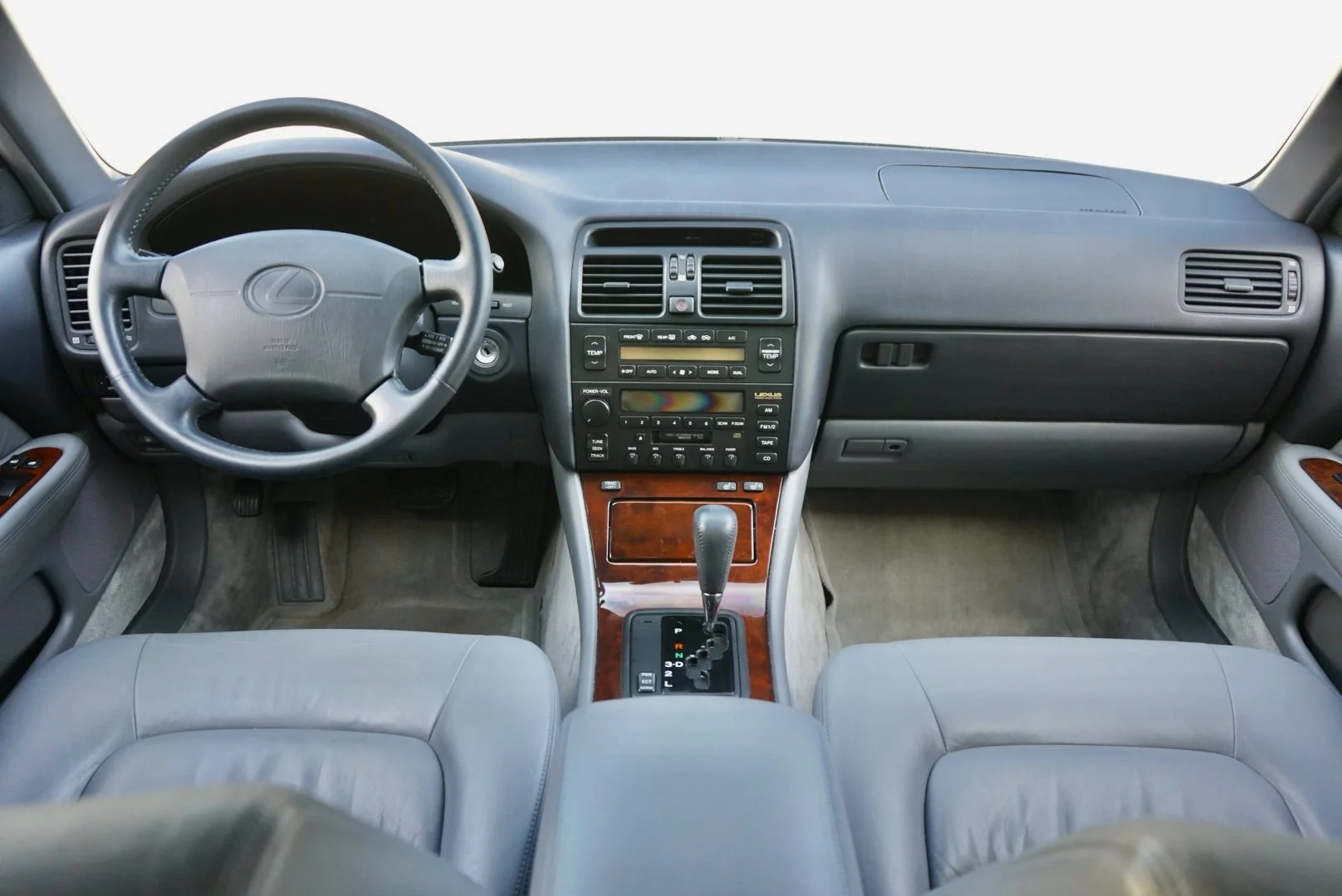 Front interior of a car showing the steering wheel, dashboard, center console, gear shift, and front seats.