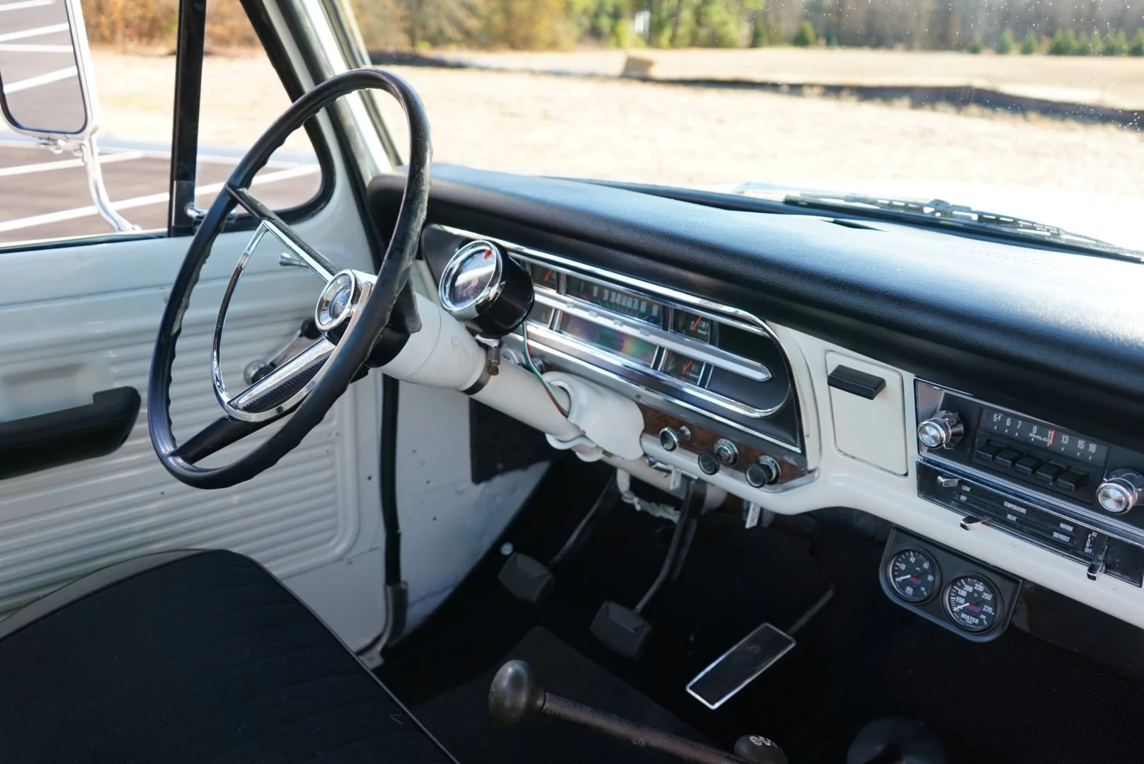 Inside the dashboard of a vintage pickup truck, featuring a classic steering wheel, analog gauges, and an old-fashioned radio.
