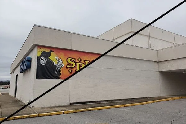 Part of a store building with a Halloween or horror-themed sign featuring a spooky clown and the word 'Spook' in yellow letters.