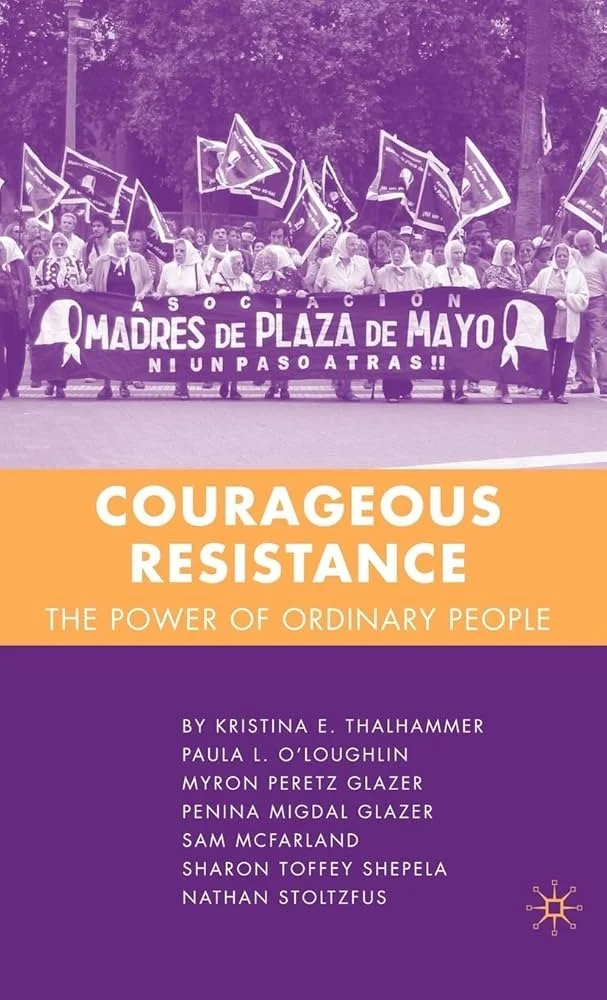A protest or rally with a large group of women holding a banner that reads "Asociación Madres de Plaza de Mayo, Ni un paso atrás!!" and waving flags. The image has a purple overlay.