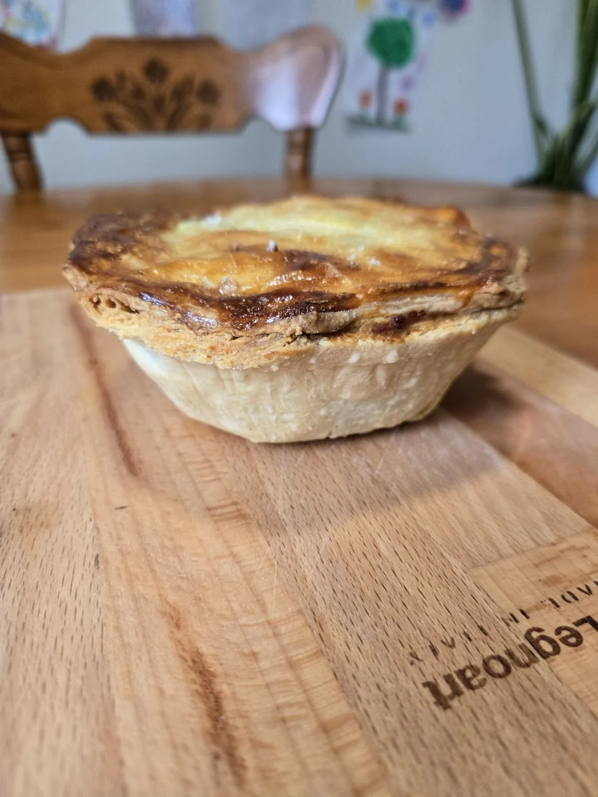 A slice of shepherd's pie on a wooden cutting board.