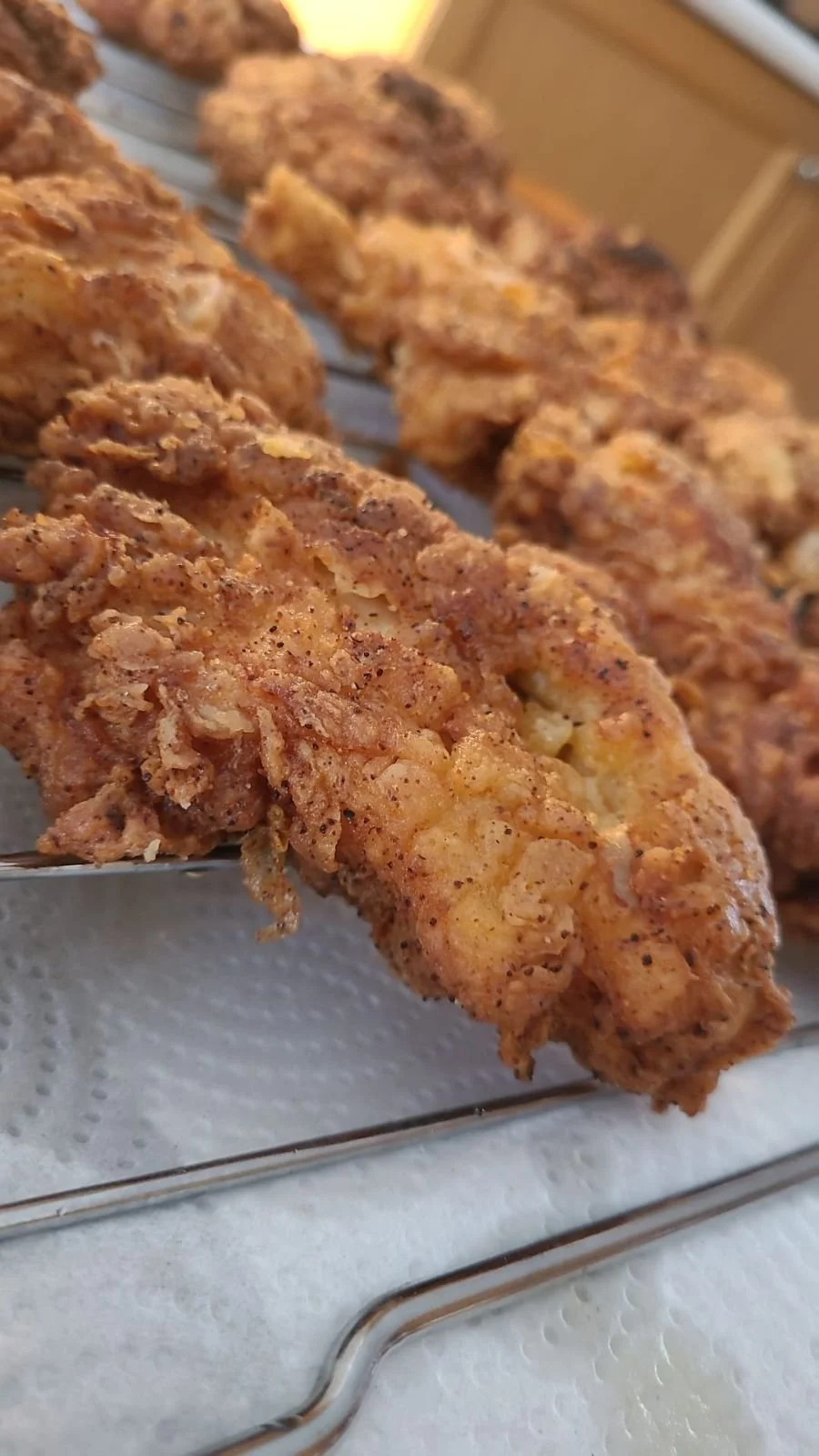 Close-up of crispy, seasoned fried chicken tenders on a wire rack.