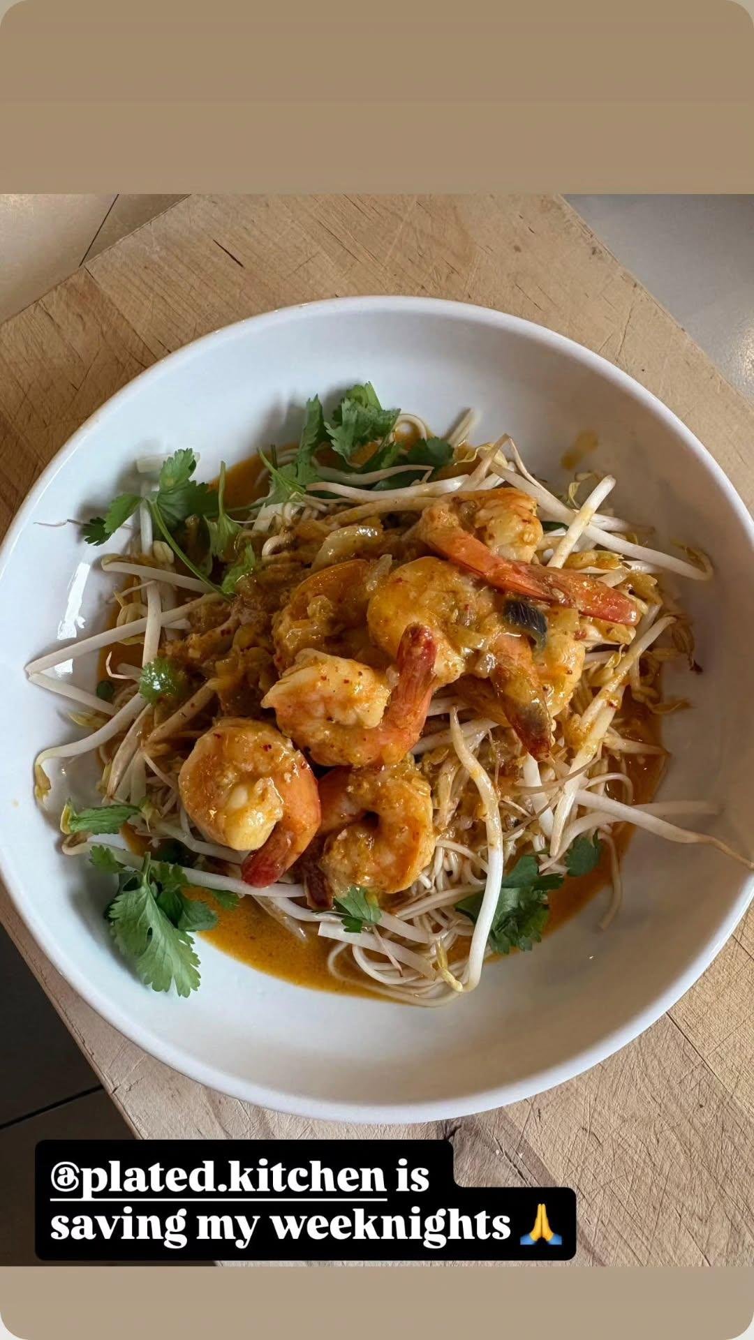Bowl of shrimp and noodles with bean sprouts, cilantro, and sauce.