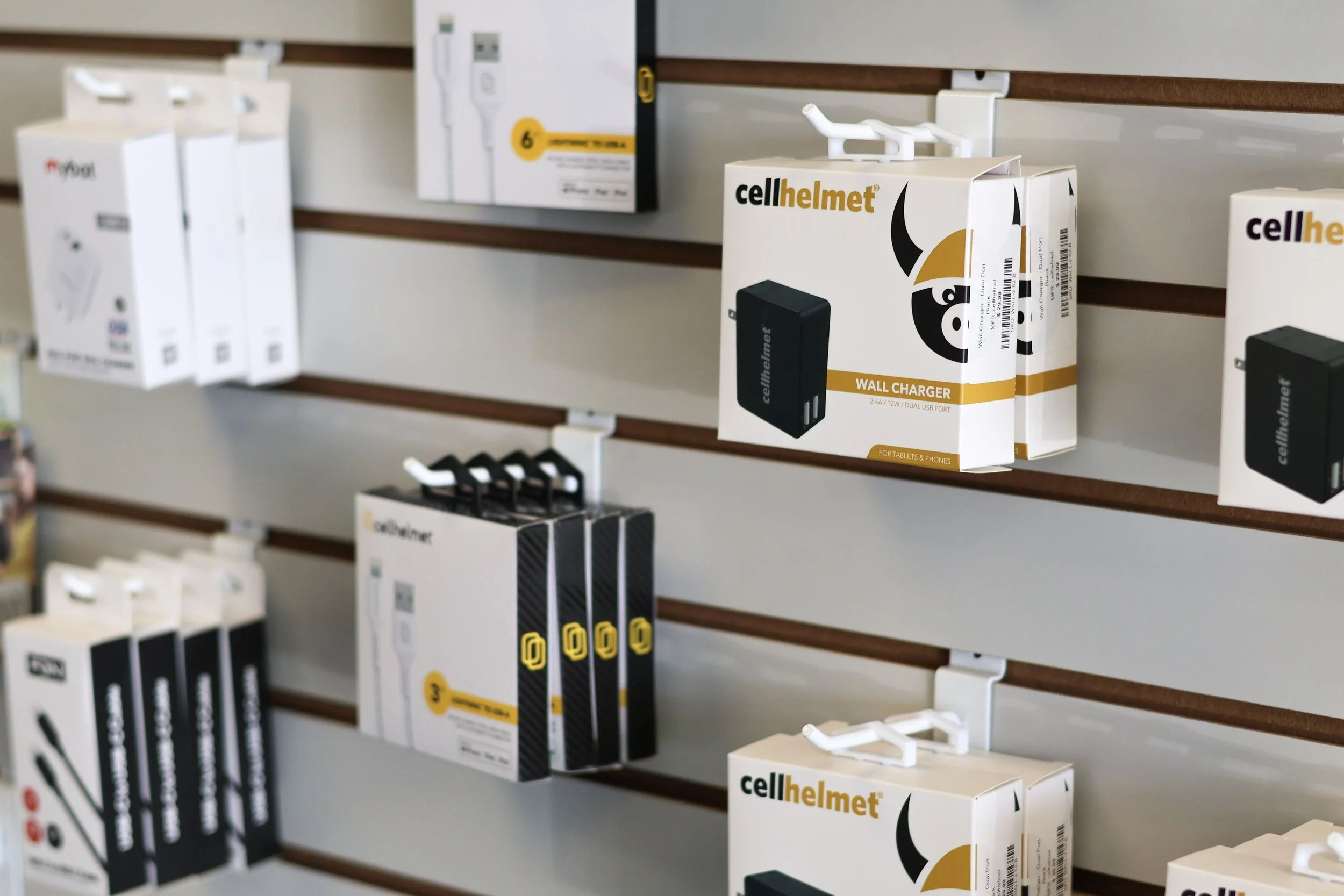 Display of cellphone accessories and chargers on store shelves, including wall chargers and phone holders.