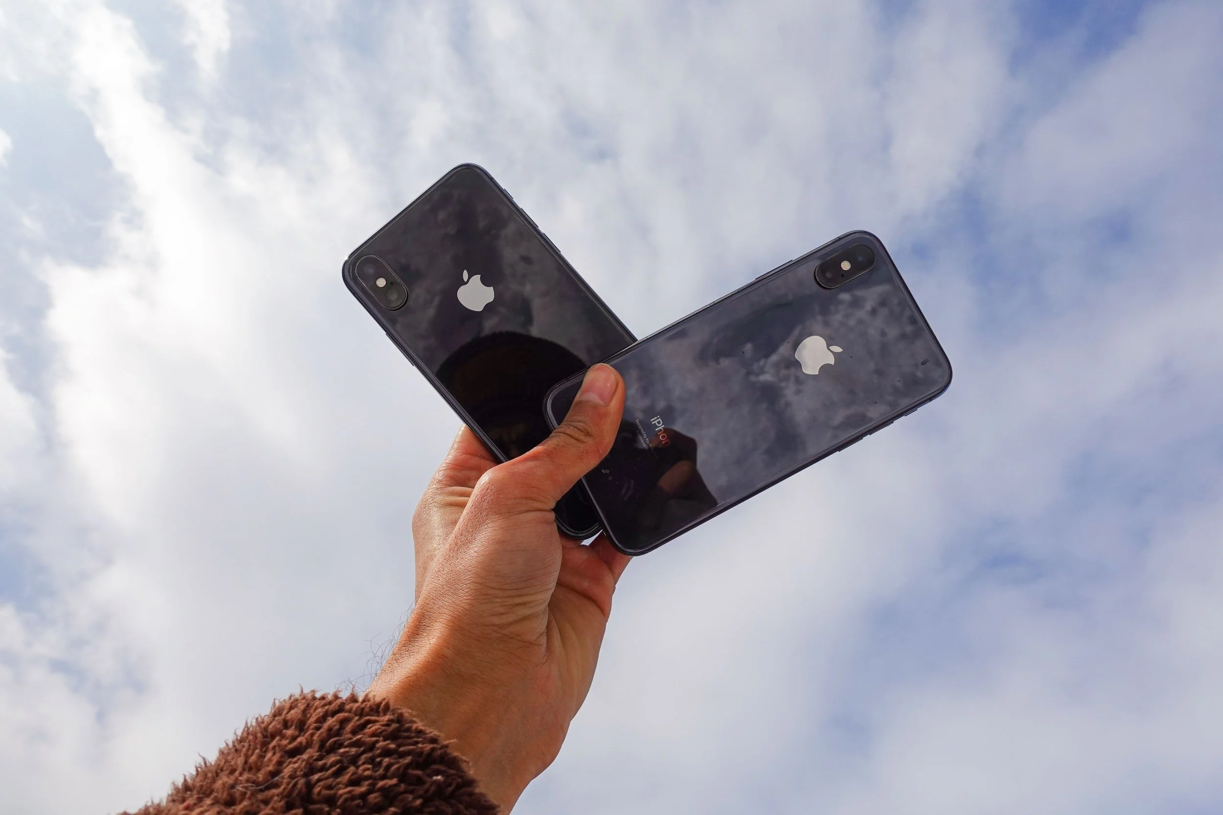 Two iPhones held in a person's hands.