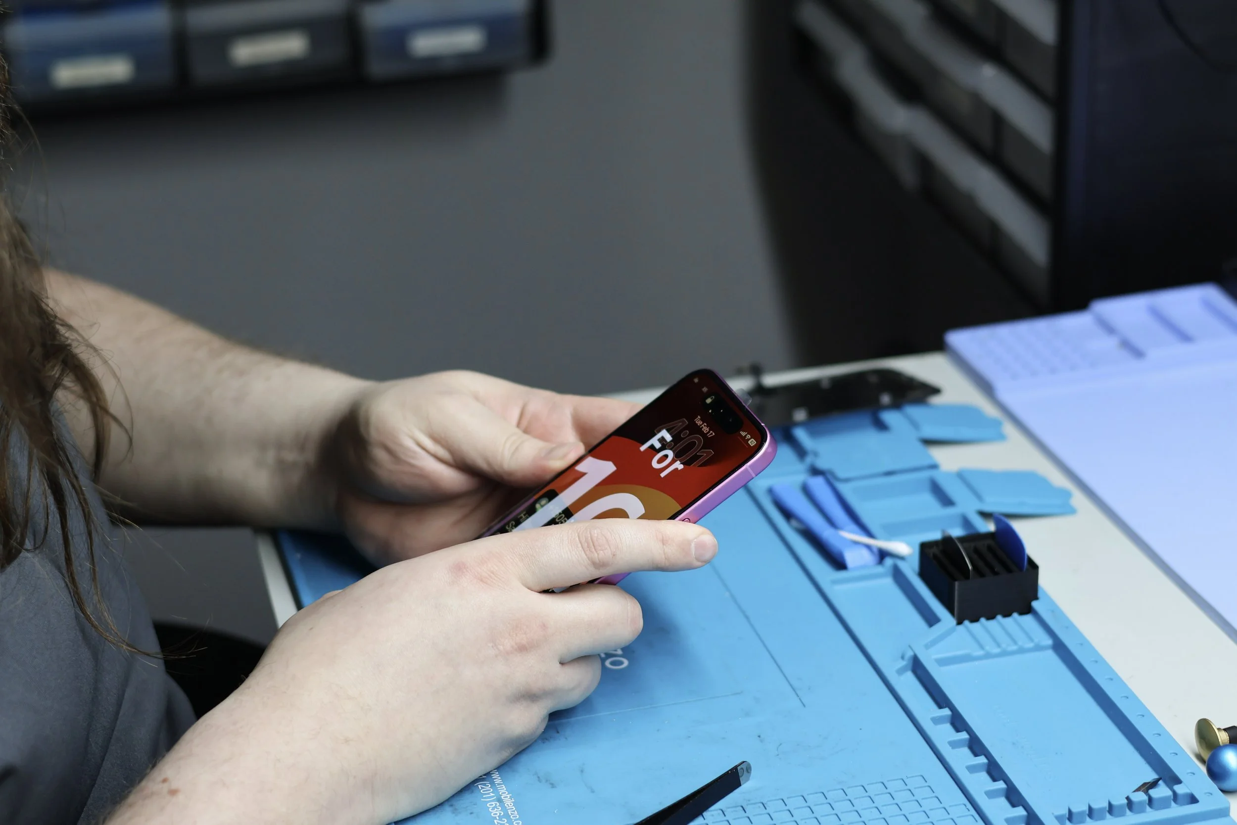 Technician performing an iPhone software diagnostic before battery replacement