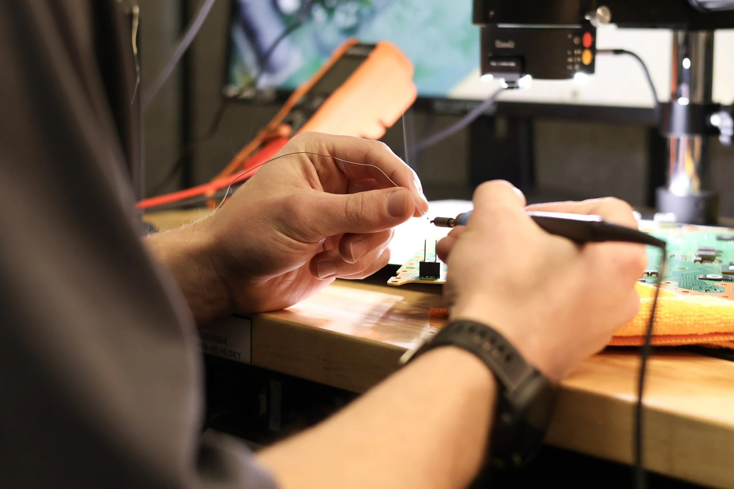 Close-up of a Phone Fix Place technician soldering phone components during a repair.