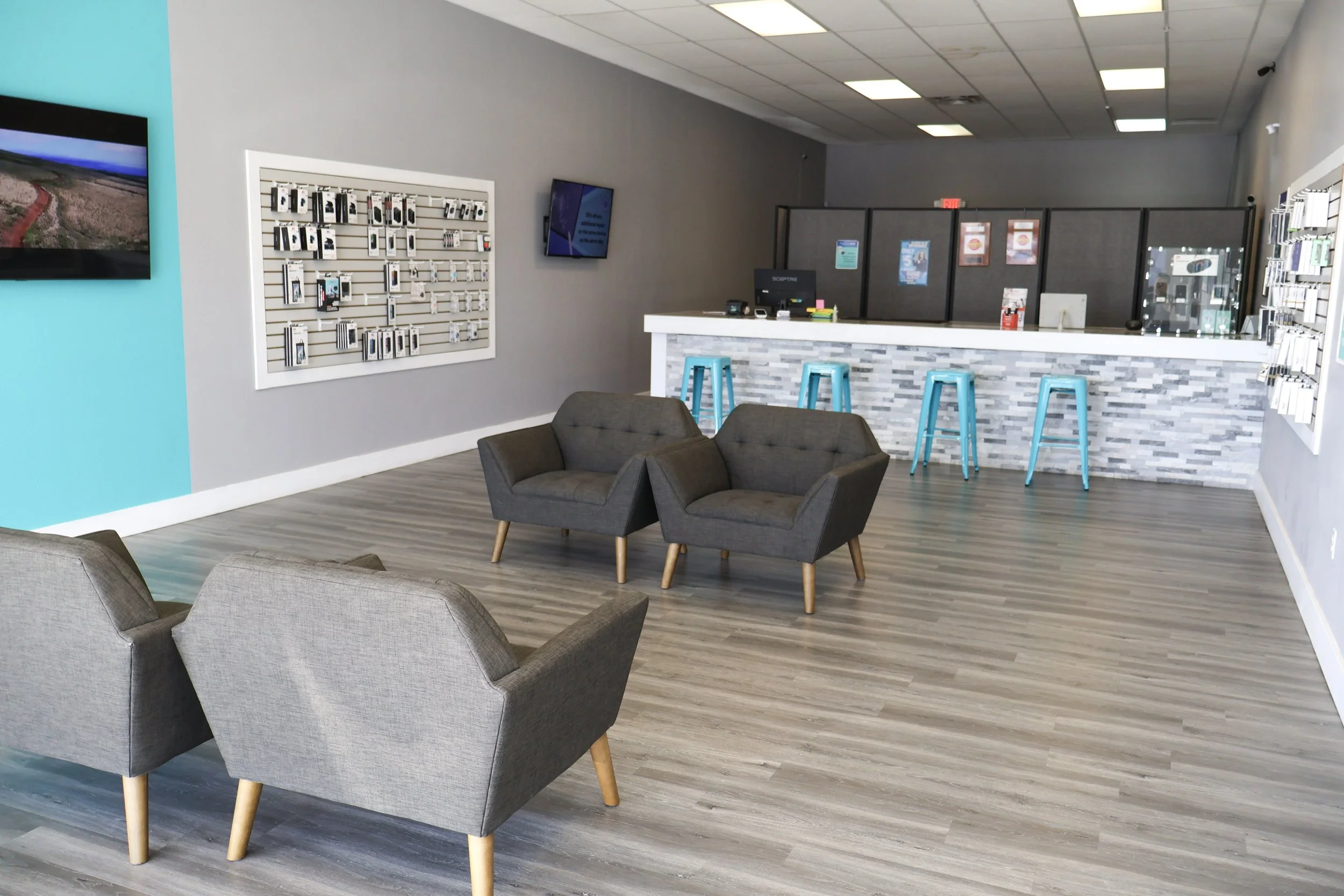 Interior of a modern retail store or service center with seating area, computer on the counter, and display screens.