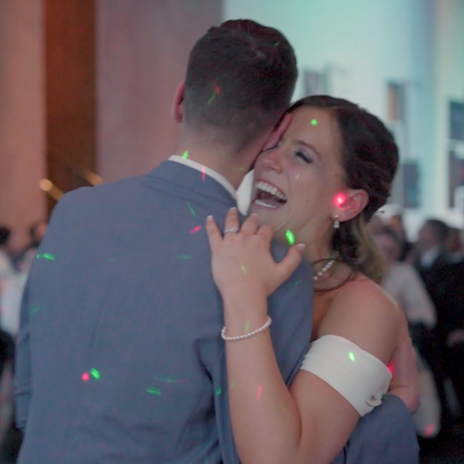 A woman and man dancing closely at a celebration, smiling and embracing.