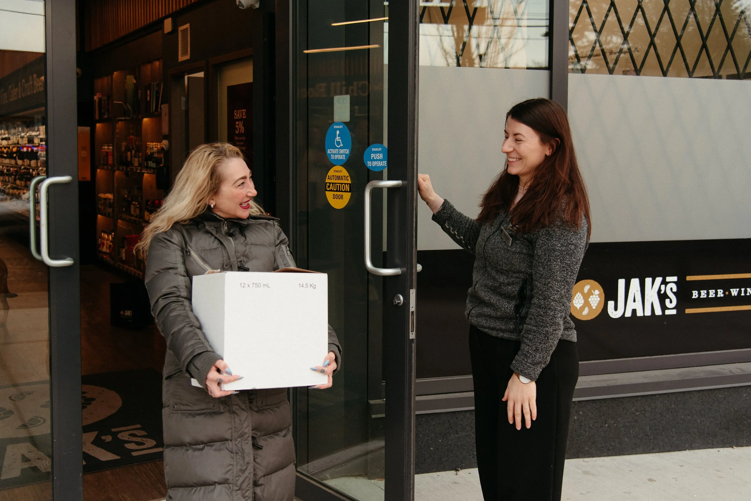 JAK's Beer Wine Spirits team member helping a customer at the store entrance, representing the company value of Caring