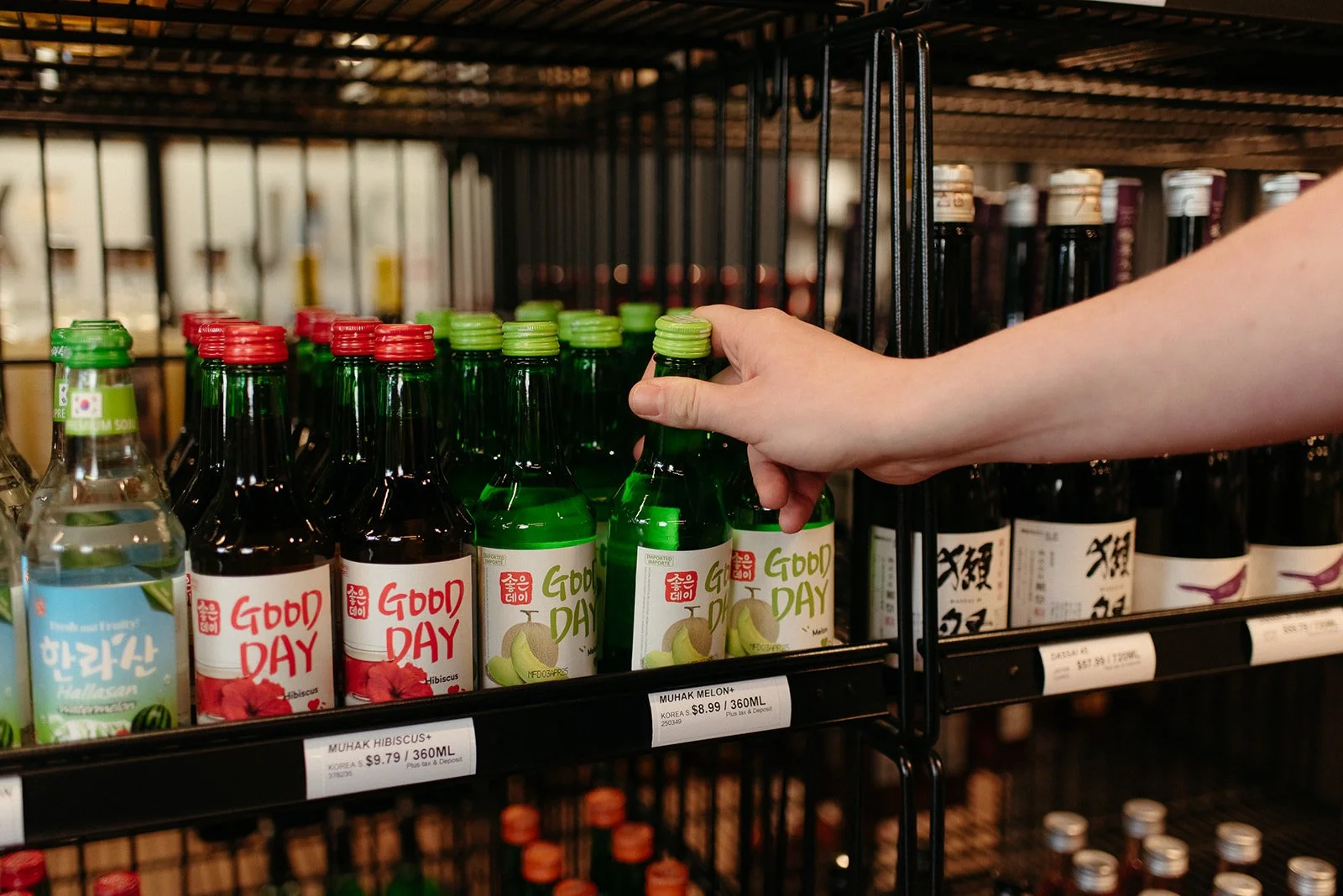 Hand selecting a ready-to-drink bottle from the shelves at a JAK's Beer Wine Spirits store in Vancouver